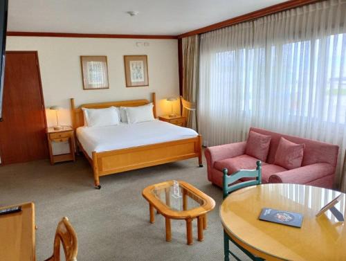 um quarto de hotel com uma cama, um sofá e uma mesa em abba Presidente Suites Puerto Montt em Puerto Montt