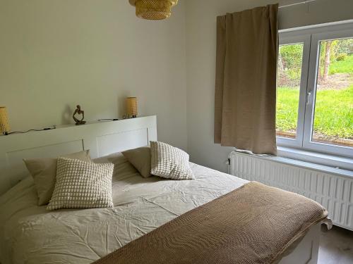a bedroom with a bed with pillows and a window at Maison 2 chambres proche de Bruxelles in Mont-Saint-Guibert