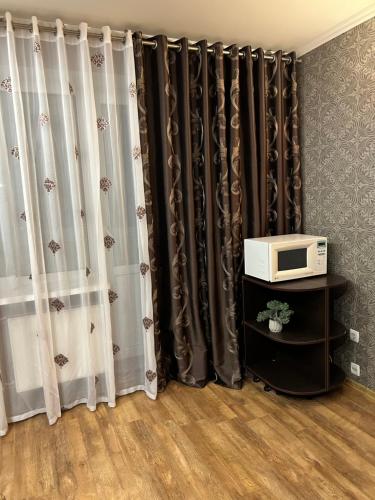 um quarto com cortinas pretas e brancas e um micro-ondas em 2-к Люкс в центре em Cherkasy