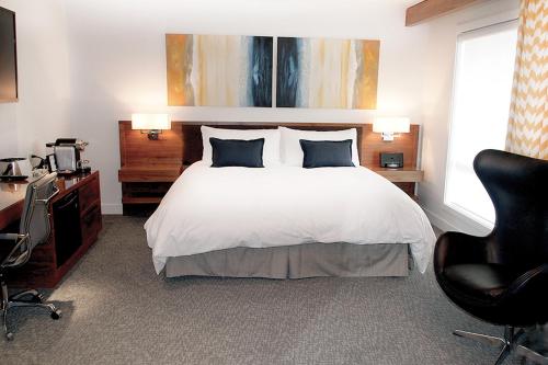 a bedroom with a bed and a desk and chairs at Qualicum Beach Inn in Qualicum Beach