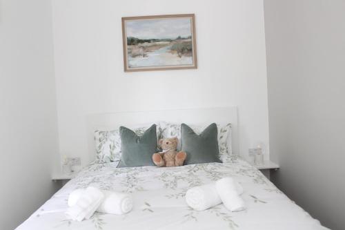 un osito de peluche sentado en una cama con almohadas en Crossways - Eastington en Claypits