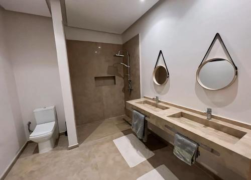 bagno con lavandino, servizi igienici e specchi. di Marrakech LUXURY VILLA a Marrakech