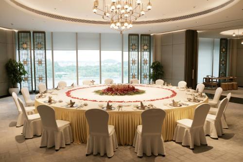 a large banquet table with white chairs and a chandelier at Vignette Collection The Xanadu Guangzhou, an IHG Hotel in Guangzhou