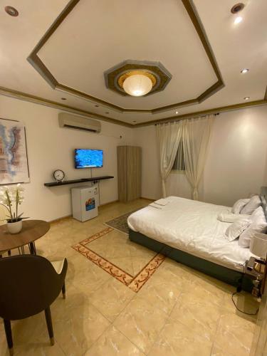a bedroom with a bed and a tv and a table at الينبوع الأخضر in Al Madinah