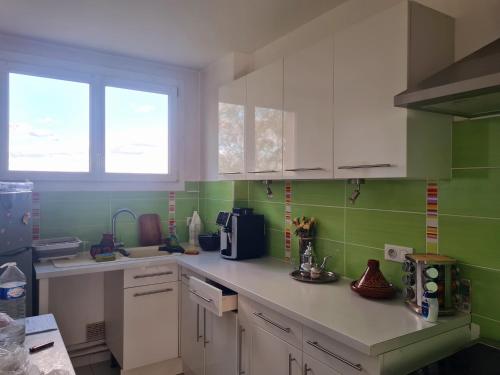 une cuisine avec des placards blancs et du carrelage vert dans l'établissement Logement entier appartement pas loin du circuit des 24, au Mans