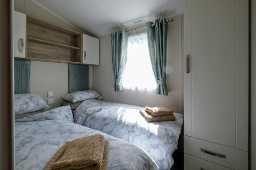2 camas en un dormitorio pequeño con ventana en 10 Beachlands en Porchfield