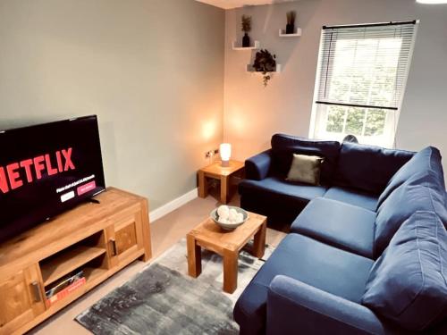 a living room with a blue couch and a tv at Lakeland Living - Devenish Manor in Enniskillen