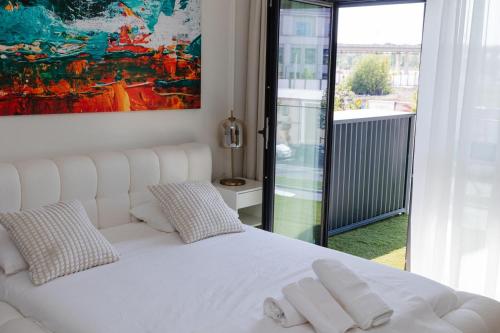 a white bed with two pillows and a painting on the wall at Studio Passion - Belgrade Waterfront in Belgrade