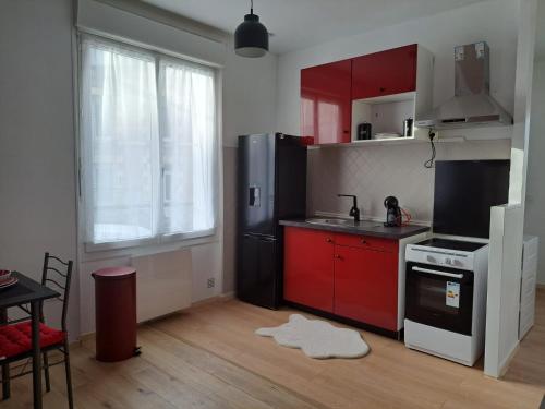 een keuken met rode kasten en een zwarte koelkast bij Confortable Apart de 3 pièces in Poitiers
