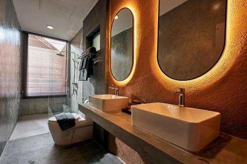 uma casa de banho com 2 lavatórios e um WC e espelhos em Baan Rai Santisuk em Ban Sok Dua