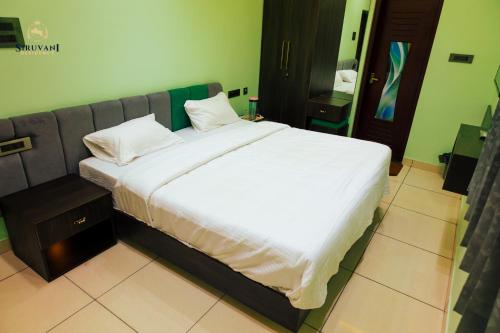 a bed with white sheets and pillows in a room at Siruvani Residency - Near Isha Foundation Coimbatore in Alāndurai