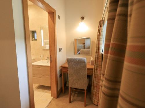ein Badezimmer mit einem Tisch, einem Stuhl und einem Spiegel in der Unterkunft Keepers Cottage in Ulverston
