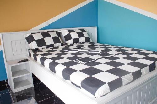 ein Bett mit schwarzen und weißen karierten Kissen darauf in der Unterkunft Studio Style Moderne in Pointe-Noire