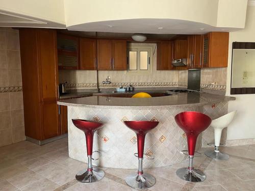 a kitchen with red stools in front of a counter at 2 Bedroom Chalet, Private Garden Ain El Sokhna in Ain Sokhna