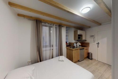 a bedroom with a white bed and a kitchen at Le Veyrier - Small studio for 2 people in the heart of the old town in Annecy