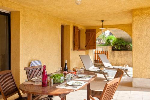 a dining table and chairs on a patio at location de vacances figuier avec jardin barbecue piscine chauffée à Calvi in Calvi