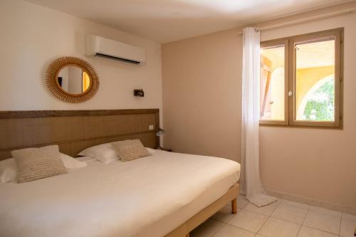 a bedroom with a bed and a mirror and a window at location de vacances figuier avec jardin barbecue piscine chauffée à Calvi in Calvi