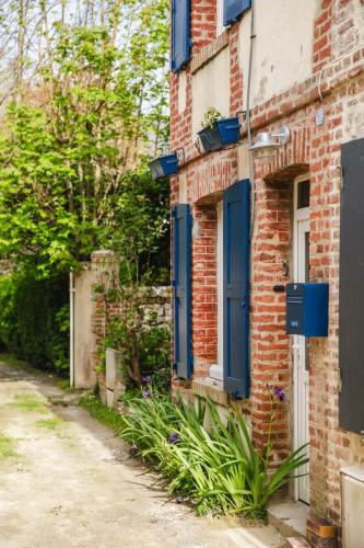 un bâtiment en briques avec des portes et des plantes bleues dans l'établissement Le Chant De La Mer - Villerville - Proche Plage, à Villerville