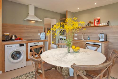 une cuisine avec une table avec un vase de fleurs dessus dans l'établissement location de vacances Olivier jardin privatif et piscine chauffée partagée, à Calvi
