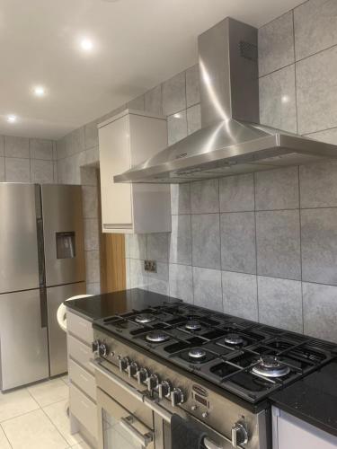 uma cozinha com um fogão e um capô de aço inoxidável em Private room renovated with standard size brown desk in SE9 6PG em Londres