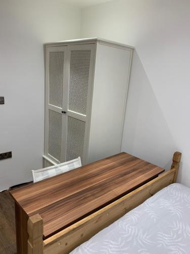 uma cama com uma cabeceira de madeira e uma janela em Private room renovated with standard size brown desk in SE9 6PG em Londres