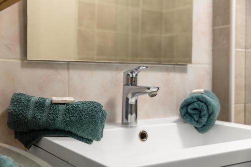 ein Waschbecken mit einem Wasserhahn und einem grünen Handtuch in der Unterkunft Studio Victoria in Aix-les-Bains