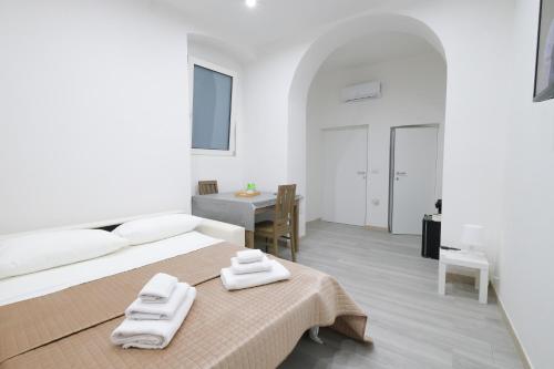 a white bedroom with a bed and a table at Antonia’s House in Bari