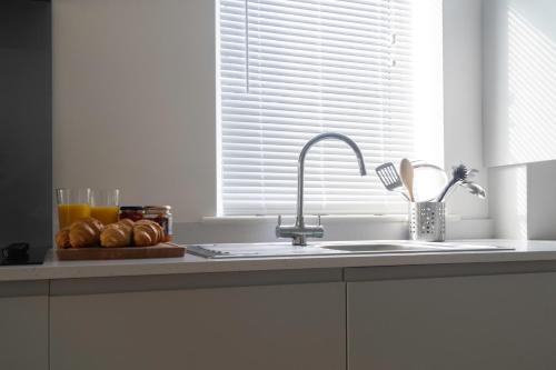 a kitchen counter with a sink and a plate of bread at Crossways - a modern two bedroom village apartment close to cheltenham in Claypits