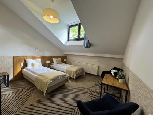 un dormitorio en el ático con 2 camas y una silla en IRIS Aparthotel, en Cracovia