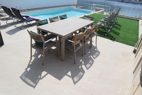 a wooden table and chairs next to a swimming pool at The Coral Villa with marina access, free ka yak and private pool - Al Dana Island Fujairah in Fujairah