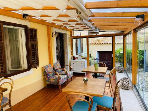 a patio with wooden tables and chairs and windows at Villa Verde Piran, Authentic Mediterranean Stay - Newly Opened in Piran