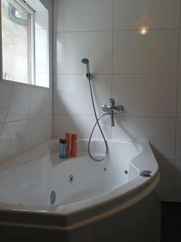 a white bath tub with a shower in a bathroom at Sveciu namai in Vikedal