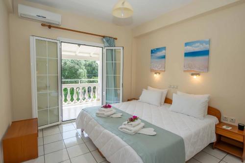 Un dormitorio con dos camas y una gran ventana. en Lea Family Resort, en Kassiopi