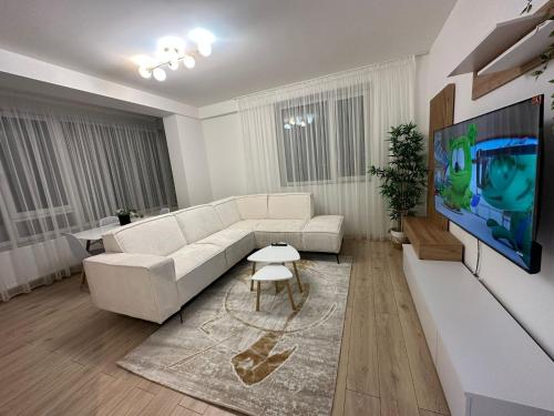 sala de estar con sofá blanco y TV de pantalla plana en Celine's Apartment, en Constanţa