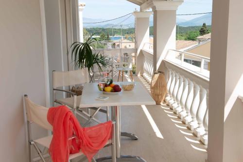 un balcón con una mesa y un bol de fruta. en Lea Family Resort, en Kassiopi