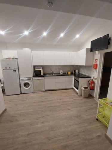 a large kitchen with white cabinets and appliances at Casa Paulinho in Portimão