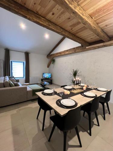ein Esszimmer mit einem Tisch und einem Sofa in der Unterkunft La Maison du Cocher in Étival-Clairefontaine