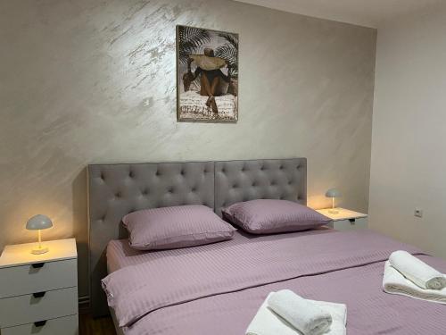 a bedroom with a bed with purple sheets and a picture on the wall at Apartman Nađa in Bileća