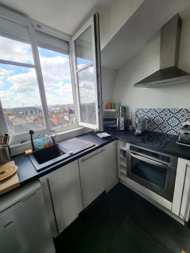 une cuisine avec un évier et un comptoir avec des fenêtres dans l'établissement Hyper centre de NANTES, dernier étage vue exceptionnelle, à Nantes