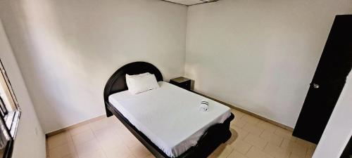 um pequeno quarto com uma cama branca num quarto em APARTAHOTEL HEFZIBA em Barranquilla