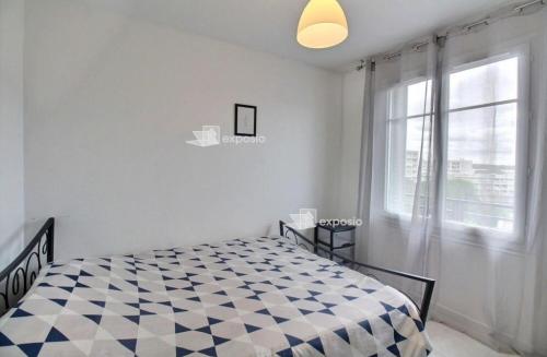una camera con un letto a scacchi di fronte a una finestra di Appartement Ris orangis a Ris-Orangis