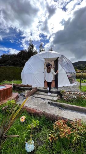 Eine Frau, die aus einem weißen Zelt spaziert. in der Unterkunft TINY HOUSE LUJOSA CASA CON JACUZZI MALLA CATAMARAN in Guatavita
