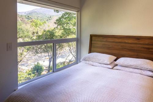 a bedroom with a bed and a large window at Sierra River House 5 min to Sequoia Park Entrance in Three Rivers