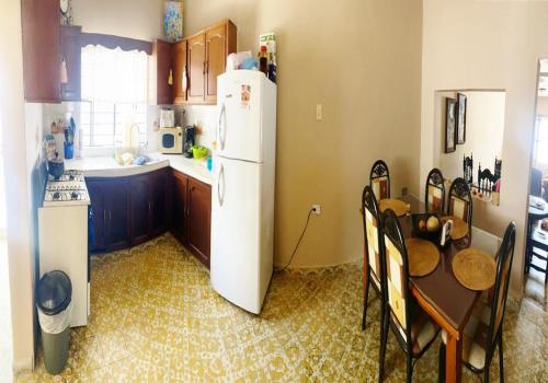 a kitchen with a white refrigerator and a table at Casa Estancia Viajera Olímpica - 7 Min Malecón in Mazatlán