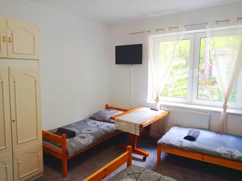 two beds in a room with a table and a window at Gdańsk tanie noclegi pokój nr 7 1-4 osobowy z łazienką na korytarzu in Gdańsk