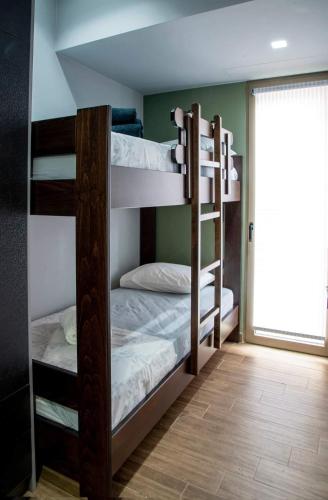 two bunk beds in a room with a window at Polytelia Apartment Karystos in Karistos