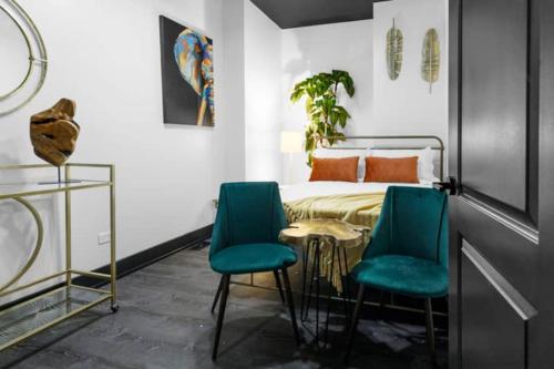 a bedroom with a bed and two blue chairs at The Black And White Suite in Chicago