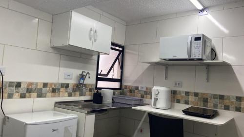 a white kitchen with a sink and a microwave at 52 LOFT quadruplo · LOFT perto da São Paulo EXPO edo metrô Jabaguara in São Paulo