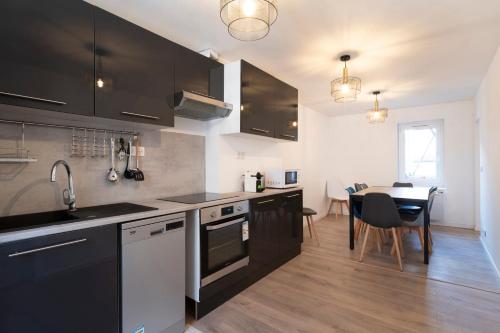 - une cuisine avec des armoires noires et une table à manger dans l'établissement Le cosmopolitain, à Metz