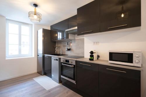 uma cozinha com armários pretos e um micro-ondas em Le cosmopolitain em Metz